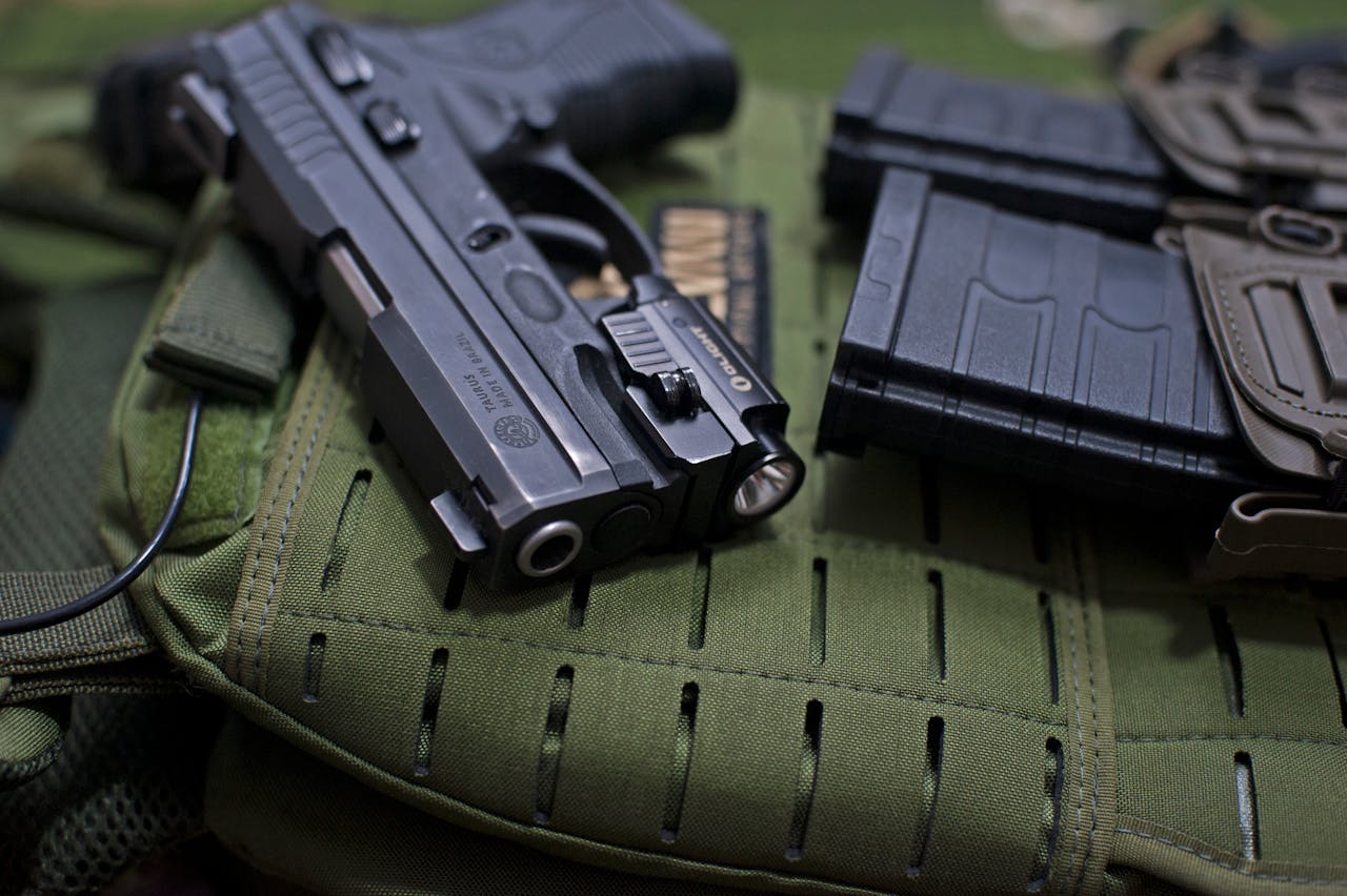 Home Handgun placed on military gear with tactical accessories, emphasizing modern defense tools.